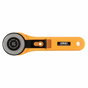 May include: A yellow rotary cutter with a black blade and a black handle. The blade is labelled "OLFA ROTARY CUTTER 45mm". The handle has the OLFA logo and "Made in Japan" printed on it.