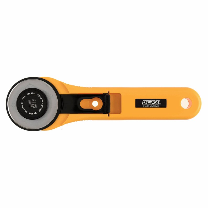 May include: A yellow rotary cutter with a black blade and a black handle. The blade is labelled "OLFA ROTARY CUTTER 45mm". The handle has the OLFA logo and "Made in Japan" printed on it.