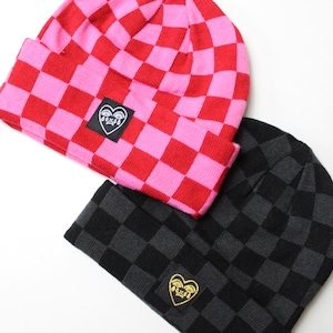 May include: Two beanies with a chequered pattern. One is red and pink, the other black and grey. Each beanie features a small patch with a heart and eye design.