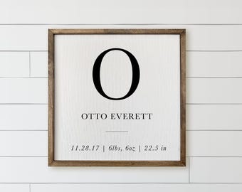 Könnte beinhalten: Ein quadratisches Holzschild mit weißem Hintergrund, das einen großen schwarzen Buchstaben O, den Namen OTTO EVERETT sowie Geburtsdaten wie 11.28.17, 6lbs, 6oz und 22.5 in in schwarzer Schriftart mit serifenlosen und Serifenschriften zeigt.