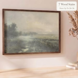 May include: A rectangular landscape painting in a dark brown wooden frame featuring a misty, muted green and grey field with trees under a soft, overcast sky. The text 7 Wood Stains Sizes Up to 26x36 inches is visible in the upper right corner.