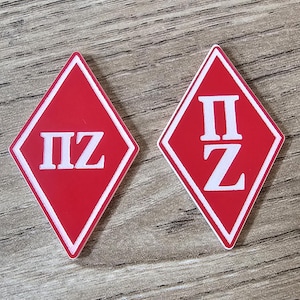 May include: Two red diamond-shaped patches with white outlines. The patches have the letters "ΠΣ" in white.
