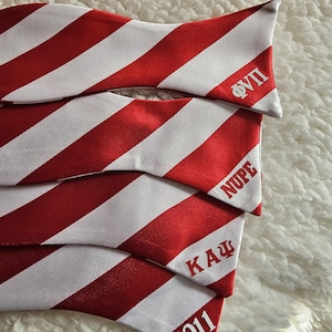 May include: Four red and white striped bow ties with white text. The top bow tie says "ΦΥΠ", the second says "NUPΕ", the third says "ΚΑΨ", and the bottom says "1911".