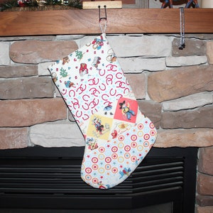 May include: A white Christmas stocking with a patchwork design featuring cowboys, horseshoes, and stars. The stocking is hanging from a hook above a fireplace.