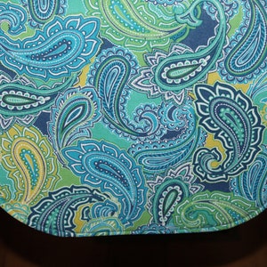 May include: A green, blue, and yellow paisley patterned table runner with a scalloped edge.