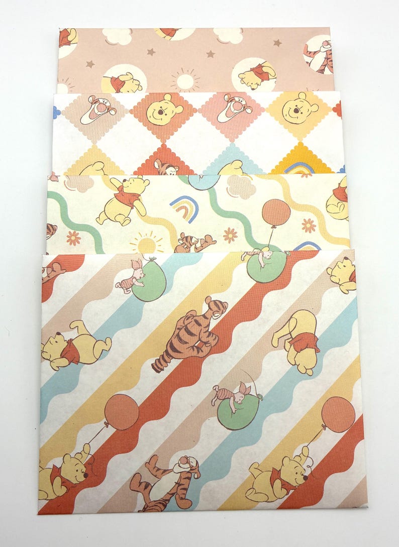 May include: A set of four rectangular envelopes featuring Winnie the Pooh and Tigger characters. The designs include patterns with clouds, stars, suns, rainbows, balloons, and wavy stripes in pastel shades of yellow, orange, blue, and green.