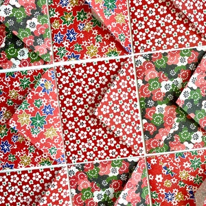 May include: A collection of nine red origami envelopes with different floral patterns. The envelopes are folded into triangles and arranged in a grid pattern.