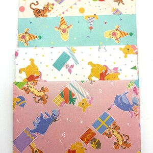 May include: A stack of five rectangular paper envelopes featuring colorful Winnie the Pooh character illustrations. The designs include Tigger, Eeyore, and Piglet with party hats, balloons, and gift boxes on yellow, white, teal, and pink backgrounds.