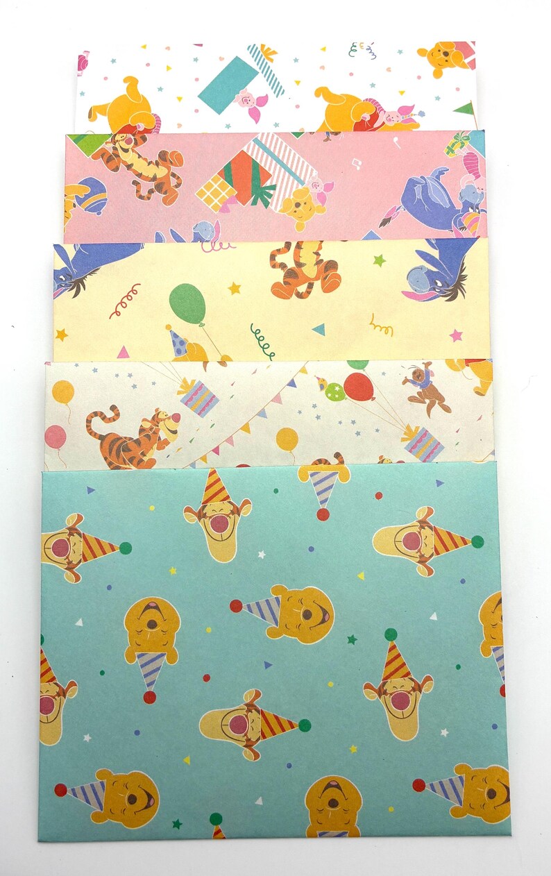 May include: A stack of five rectangular paper envelopes featuring Winnie the Pooh characters. The designs include various patterns with Tigger, Eeyore, and Piglet, decorated with colorful balloons, party hats, gift boxes, and confetti on pastel backgrounds.