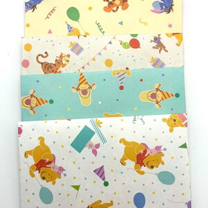 May include: A set of five rectangular paper envelopes featuring Winnie the Pooh characters including Tigger, Eeyore, and Piglet. The envelopes display colorful party-themed patterns with balloons, gift boxes, and party hats on pink, yellow, white, and teal backgrounds.