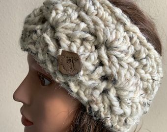 May include: A white crocheted headband with a brown button featuring the text "Tiny Mountain".