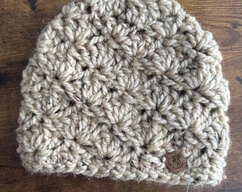 May include: A beige crocheted beanie with a brown leather tag that says "Craft Mountain".