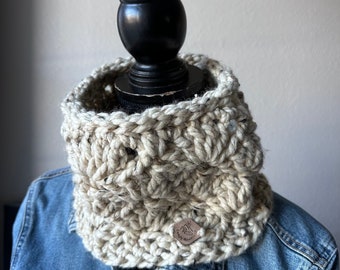 May include: A cream-colored crocheted neck warmer with a brown leather tag that says "Cozy Knits".