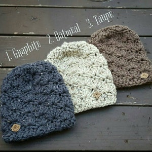 May include: Three crocheted hats in different colors: graphite, oatmeal, and taupe. Each hat has a small leather tag with the word "Made with Love" on it.
