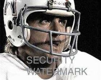 Puede incluir: Un jugador de fútbol americano con un casco blanco con rayas rojas y azules y una máscara facial. El casco tiene un logotipo en el lateral que dice "A's". El jugador lleva una camiseta blanca con un número azul "7" en la parte delantera.