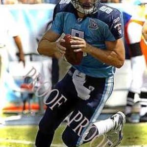 May include: A football player wearing a blue and white jersey runs with the ball. He is wearing a white helmet with a blue stripe. The player is on a green pitch.