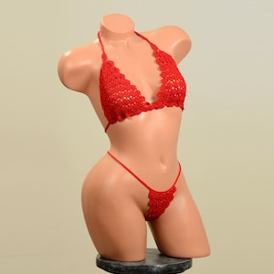 Puede incluir: Conjunto de bikini rojo de ganchillo. La parte superior es de estilo halter con forma triangular. La parte inferior es de estilo tanga con un borde festoneado.