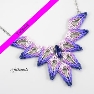May include: A statement necklace with a silver chain. The necklace has a fan-shaped design, crafted from purple, lavender, and silver beads. A large, dark blue crystal is at the centre. The text "Tutorial" and "AjaBeads" are visible.