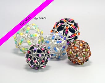 Puede incluir: Cinco esferas decorativas con cuentas de varios colores, incluyendo arcoíris, azul, negro y naranja. Las esferas tienen un diseño geométrico calado. La imagen incluye el texto "Tutorial" y "AjaBeads".