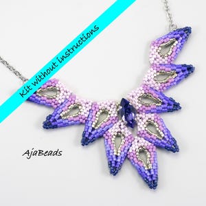 May include: A statement necklace crafted from beads in purple, lavender, and silver, with a dark blue central gem. The necklace has a fan-shaped design and a silver chain. Text reads "Kit without instructions" and "AjaBeads".