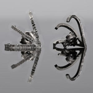 May include: A pair of silver earrings with geometric designs. The earrings are made of metal and have a textured finish.