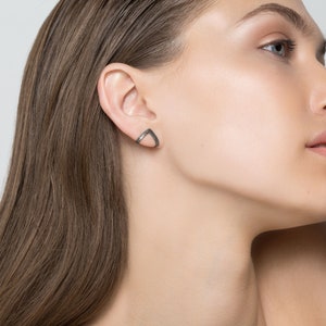May include: A pair of silver triangle shaped earrings with a black oxidized finish.
