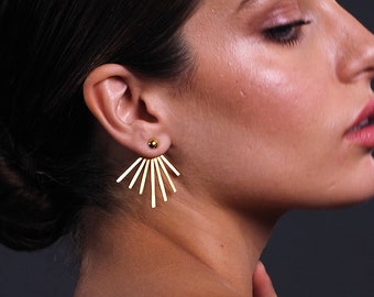 May include: Gold ear cuff earrings with a fan-shaped design. The earrings are made of thin metal bars that radiate out from a small gold ball.