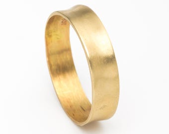 May include: A gold-colored ring with a slightly curved design. The ring has a smooth, polished surface and a simple, elegant style. The ring is a band style and is likely made of brass or gold.