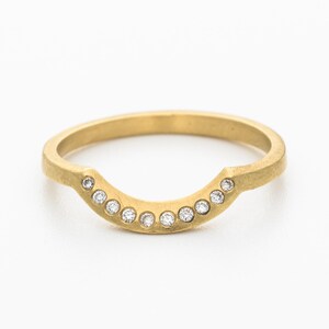 May include: A gold band ring with a curved, half-circle design set with small diamonds.