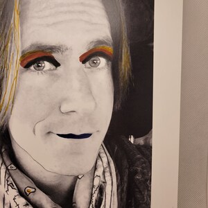 May include: A black and white portrait of a person with long hair. The person is wearing a bandana with a white and black pattern. The person has red and gold eyeshadow and blue lipstick.