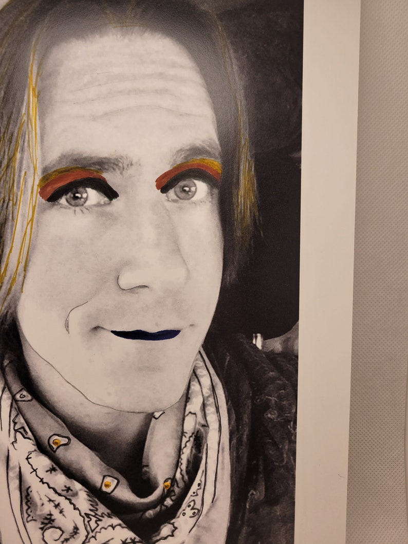 May include: A black and white portrait of a person with long hair. The person is wearing a bandana with a white and black pattern. The person has red and gold eyeshadow and blue lipstick.