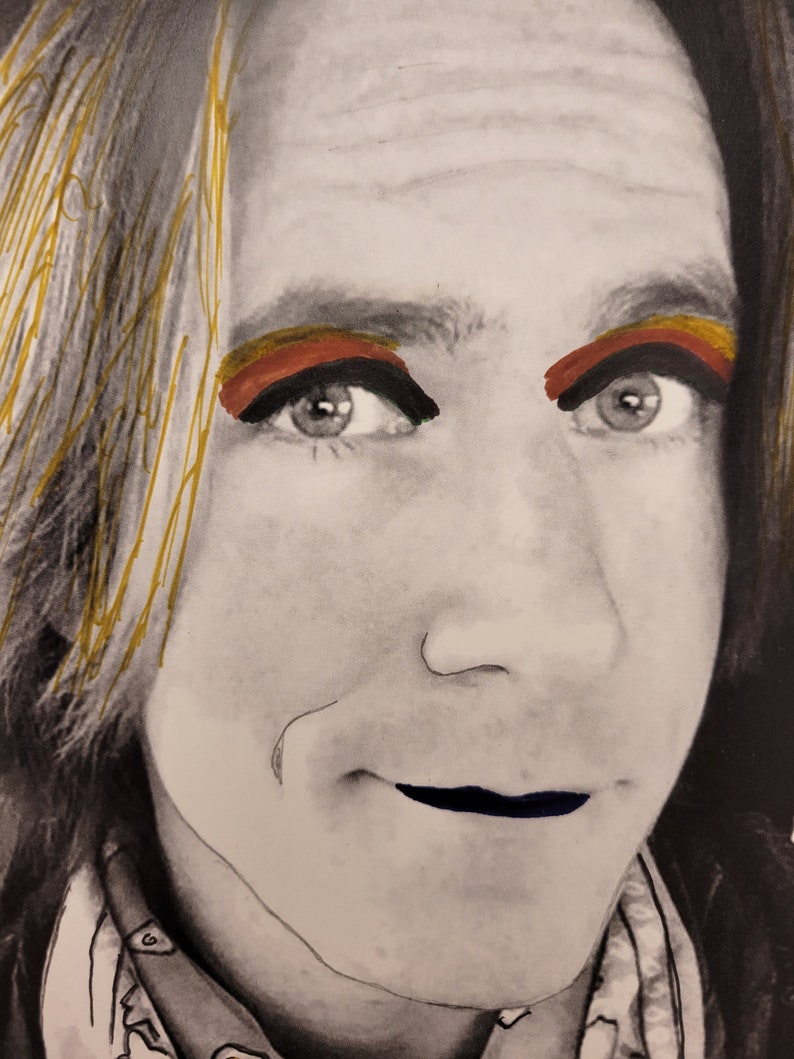 May include: A black and white portrait of a person with gold, red and orange eyeshadow. The person is wearing a black shirt and has a serious expression.