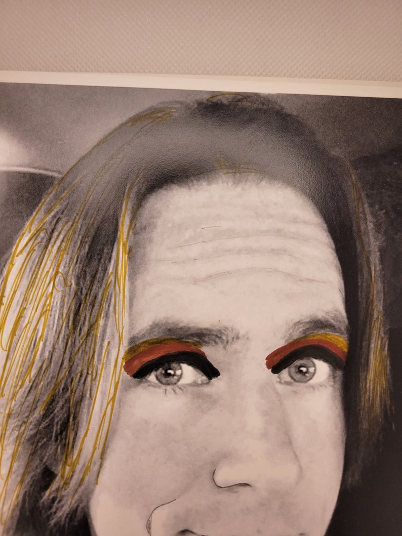 May include: A black and white photograph of a person's face with gold highlights in their hair. The person is wearing red and yellow eyeshadow.