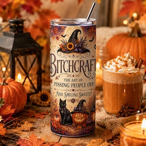 Puede incluir: Un vaso cilíndrico con pajita de metal que presenta un diseño otoñal con un gato negro, una calabaza de Halloween y hojas de otoño. El texto dice: BITCHCRAFT THE ART OF PISSING PEOPLE OFF AND SMILING SWEETLY, con un fondo de luna llena.