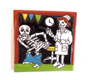 May include: Square ceramic tile featuring a Day of the Dead theme. The image depicts a skeleton patient and a skeleton nurse with a syringe. The background is black with a red border, and the scene includes a clock and colorful bunting.