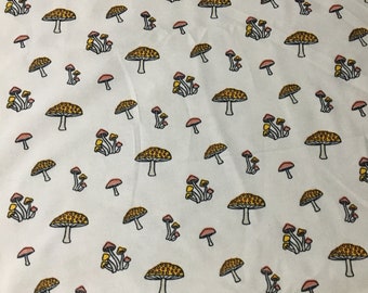 May include: White fabric with a repeating pattern of yellow and pink mushrooms. The mushrooms have white stems and brown spots on the caps.