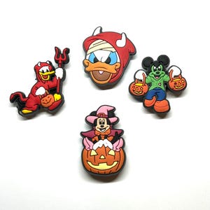 K&ouml;nnte beinhalten: Vier farbenfrohe Halloween-Schuhanh&auml;nger mit Zeichentrickfiguren. Einer ist eine rote Teufelsente mit einem Dreizack, ein anderer ist Donald Duck in einem Mumienkost&uuml;m und Micky Maus als Frankenstein. Minnie Maus ist als Hexe auf einem K&uuml;rbis verkleidet.