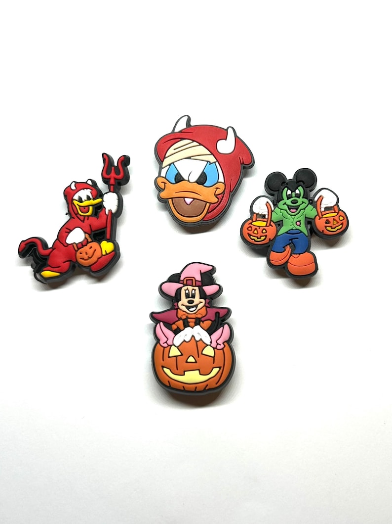 K&ouml;nnte beinhalten: Vier farbenfrohe Halloween-Schuhanh&auml;nger mit Zeichentrickfiguren. Einer ist eine rote Teufelsente mit einem Dreizack, ein anderer ist Donald Duck in einem Mumienkost&uuml;m und Micky Maus als Frankenstein. Minnie Maus ist als Hexe auf einem K&uuml;rbis verkleidet.