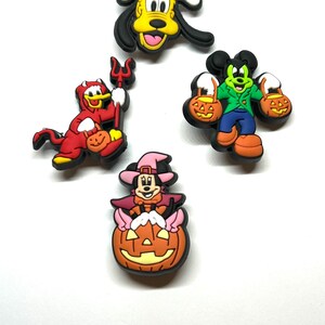 K&ouml;nnte beinhalten: Eine Sammlung von Halloween-Charms mit Charakteren. Die Charms zeigen Pluto, Donald Duck als Teufel, Mickey Mouse und Minnie Mouse. Jeder Charm ist farbenfroh und mit Halloween-Elementen wie K&uuml;rbissen und Kost&uuml;men gestaltet.