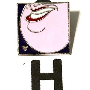 May include: Square enamel pin featuring a stylized mouth with a red, white, and silver design on a pink background. The pin has a silver border and a dark blue edge. A small Mickey Mouse icon is visible. A large black letter "H" is below the pin.