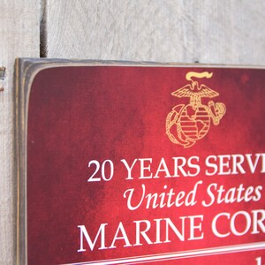 May include: A red wooden sign with the United States Marine Corps emblem and the text "20 YEARS SERVED United States MARINE CORPS".