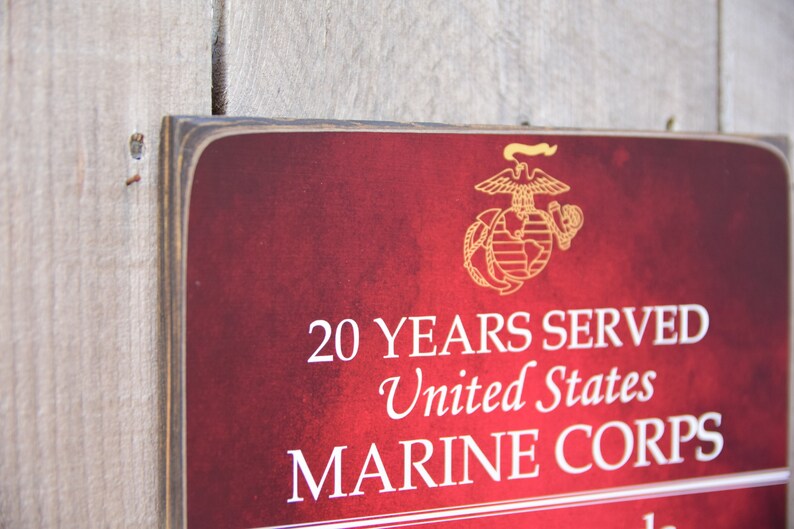 May include: A red wooden sign with the United States Marine Corps emblem and the text "20 YEARS SERVED United States MARINE CORPS".