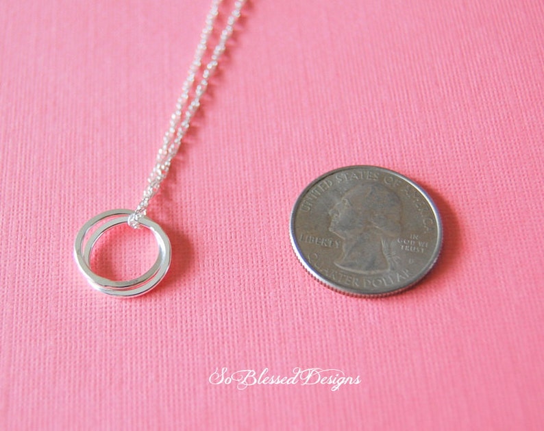 Pu&ograve; includere: Collana d'argento con ciondolo a doppio anello. Il ciondolo &egrave; circa delle dimensioni di una moneta da 25 centesimi di dollaro americano.