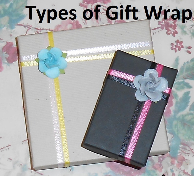 May include: Two gift boxes wrapped in different styles. One box is wrapped in brown paper with yellow and white ribbon and a light blue flower. The other box is wrapped in black paper with pink and black ribbon and a gray flower.