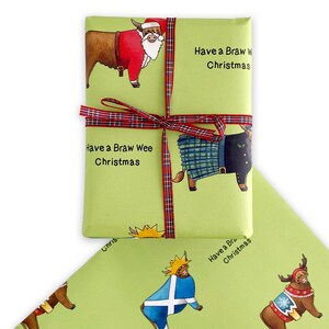 May include: Green wrapping paper featuring a festive Scottish Highland cow design. The cow is wearing a Santa hat and a red suit. The text "Have a Braw Wee Christmas" is printed on the paper.