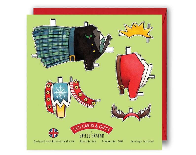 May include: A green card with a paper doll design featuring a Santa Claus, a Scottish man, and a reindeer. The card has the text "YETI CARDS & GIFTS by SHELLI GRAHAM" and "Designed and Printed in the UK. Blank inside. Product No. COW. Envelope Included."