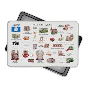May include: A rectangular metal tray featuring a colorful illustration of the Yorkshire Alphabet. The design includes various landmarks, foods, and cultural symbols of Yorkshire, England. The tray is set against a black background.
