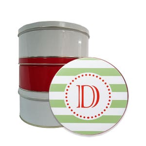 May include: A three-tiered round cookie tin with a gray, red, and green striped lid. The lid has a white circle with red polka dots and the letter "D" in red.