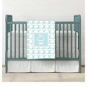 May include: A light blue baby blanket with a white pattern of stylized birds and the monogram "WCP" in a light blue square.