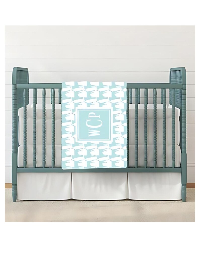 May include: A light blue baby blanket with a white pattern of stylized birds and the monogram "WCP" in a light blue square.